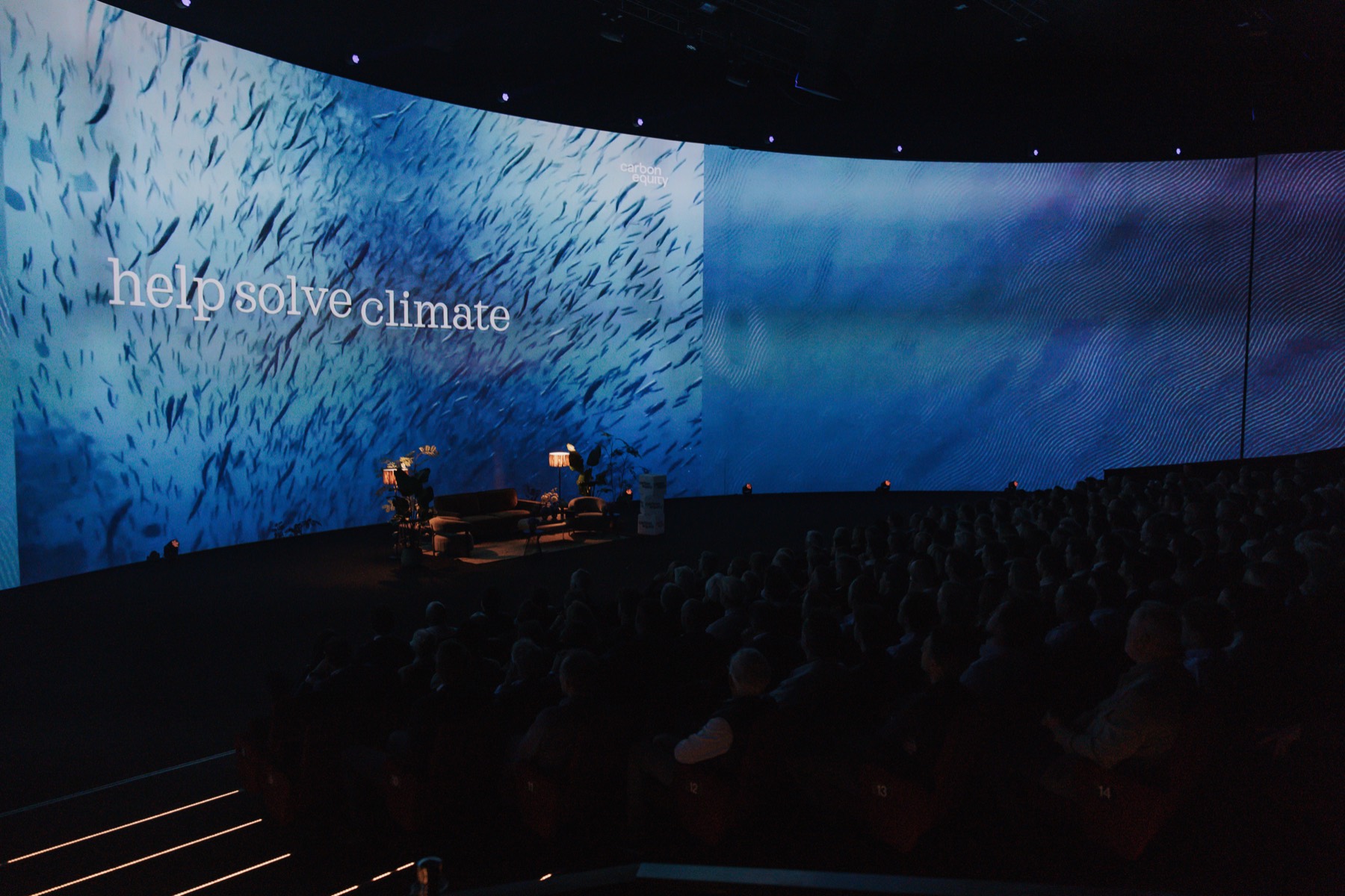 Panel on stage in front of a giant curved screen