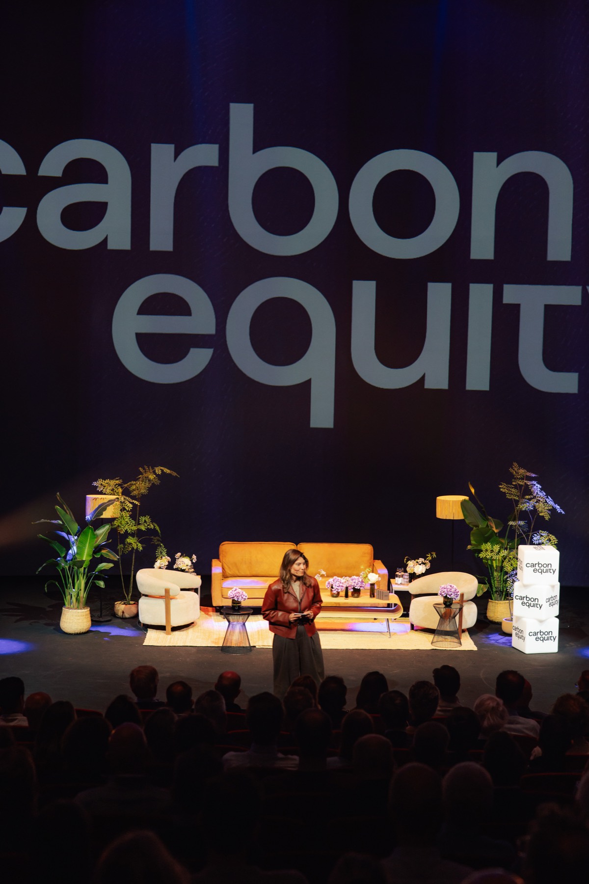Fireside chat on a stage decorated with plants