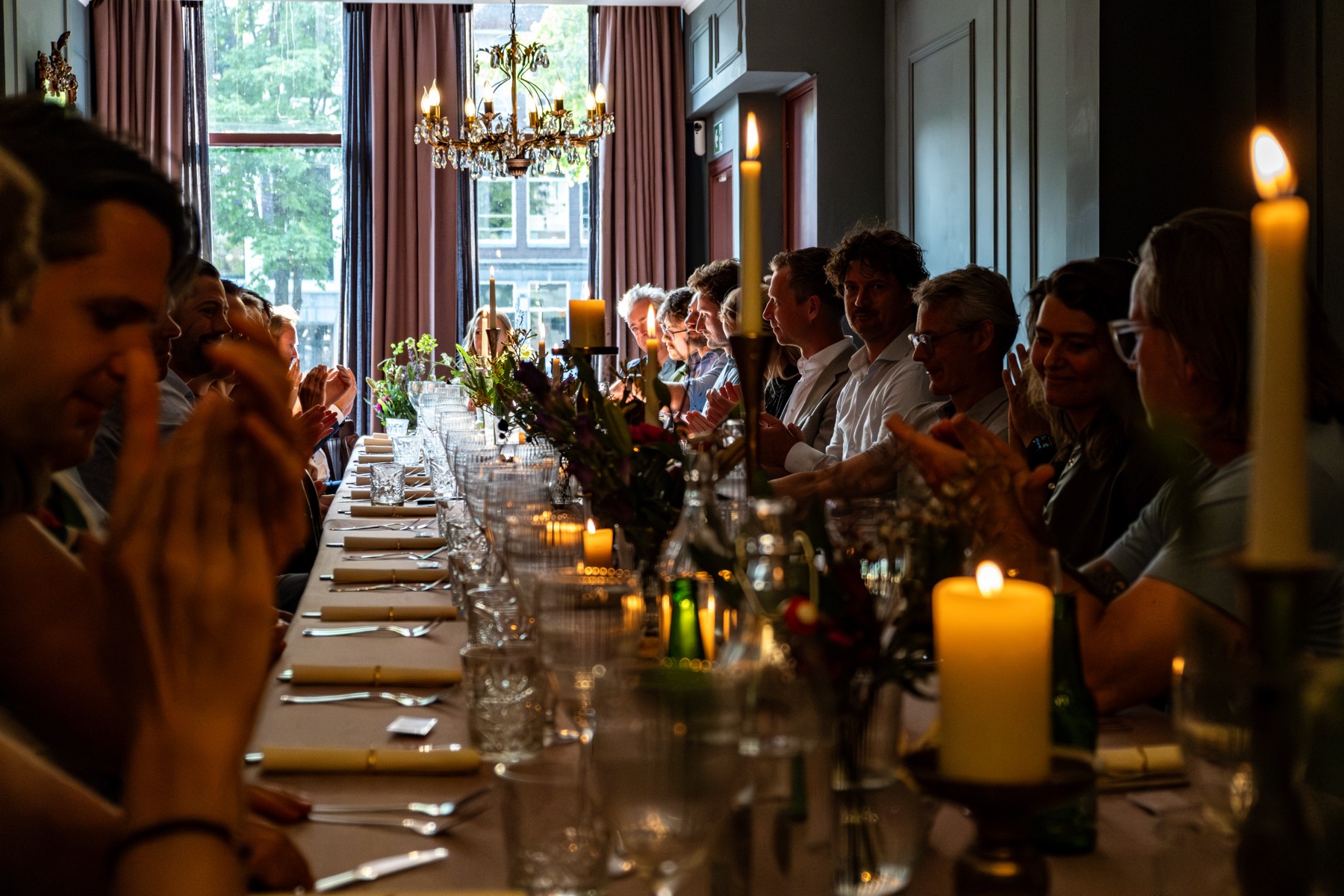 Long dinner table lit by candles and chandeliers