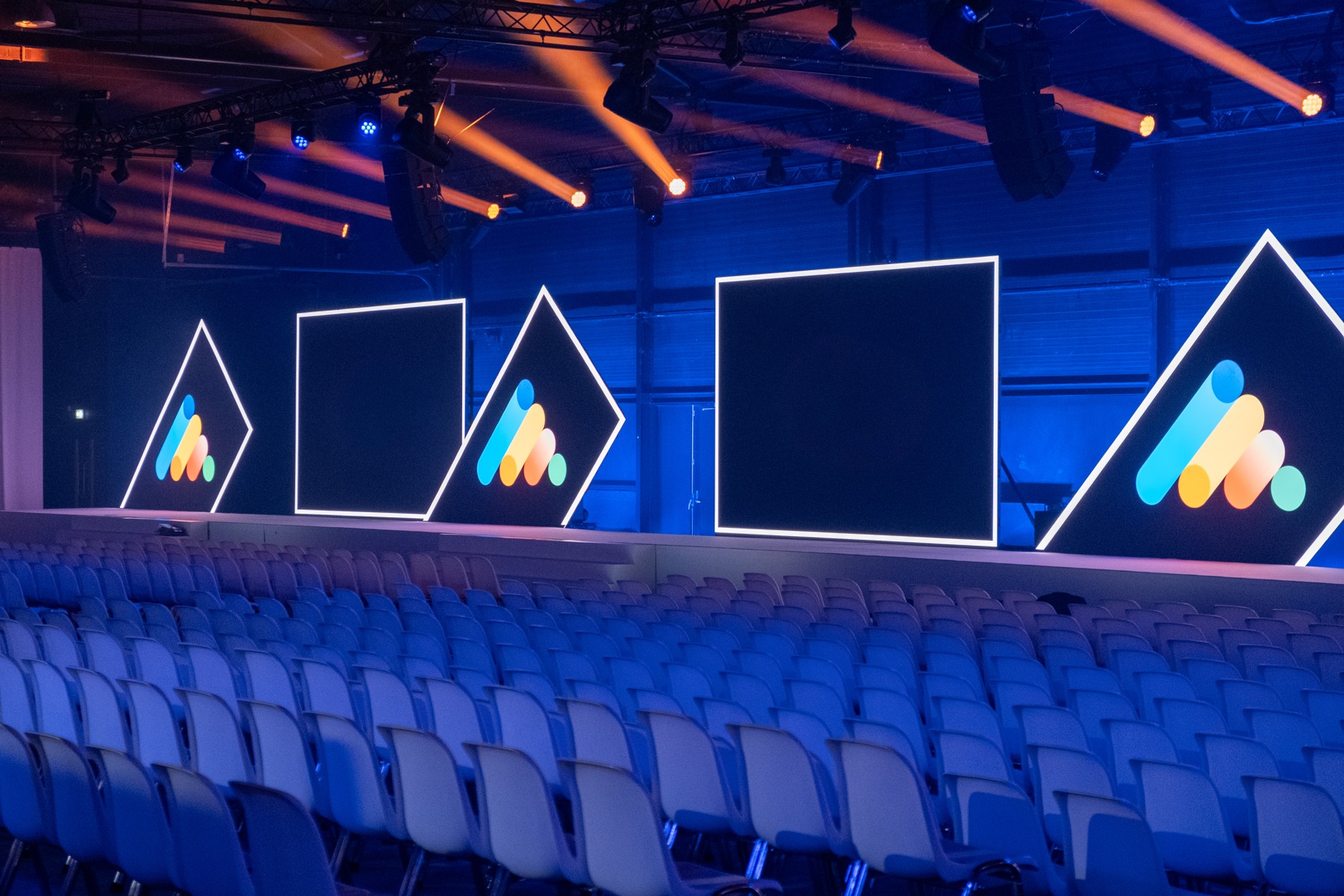 Conference stage with screens and rows of blue seats