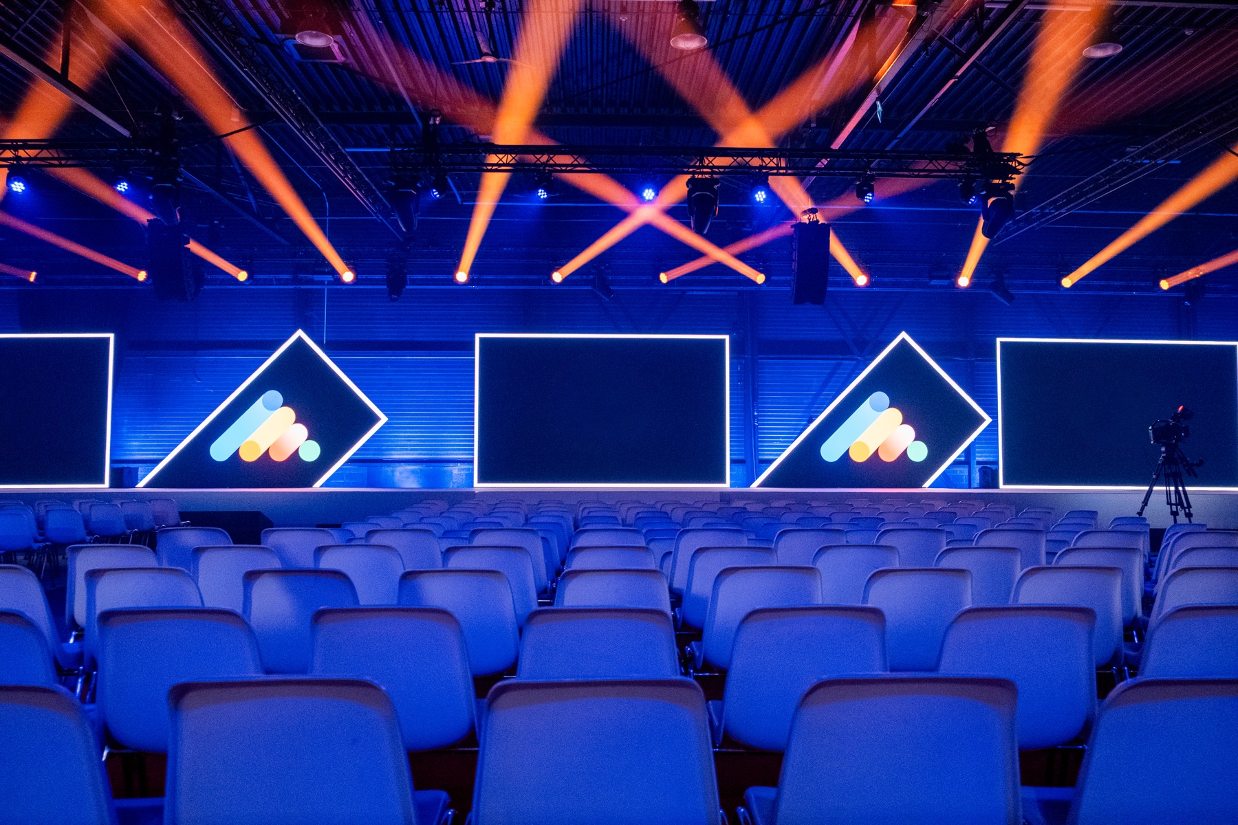 Conference hall with orange light beams above the stage